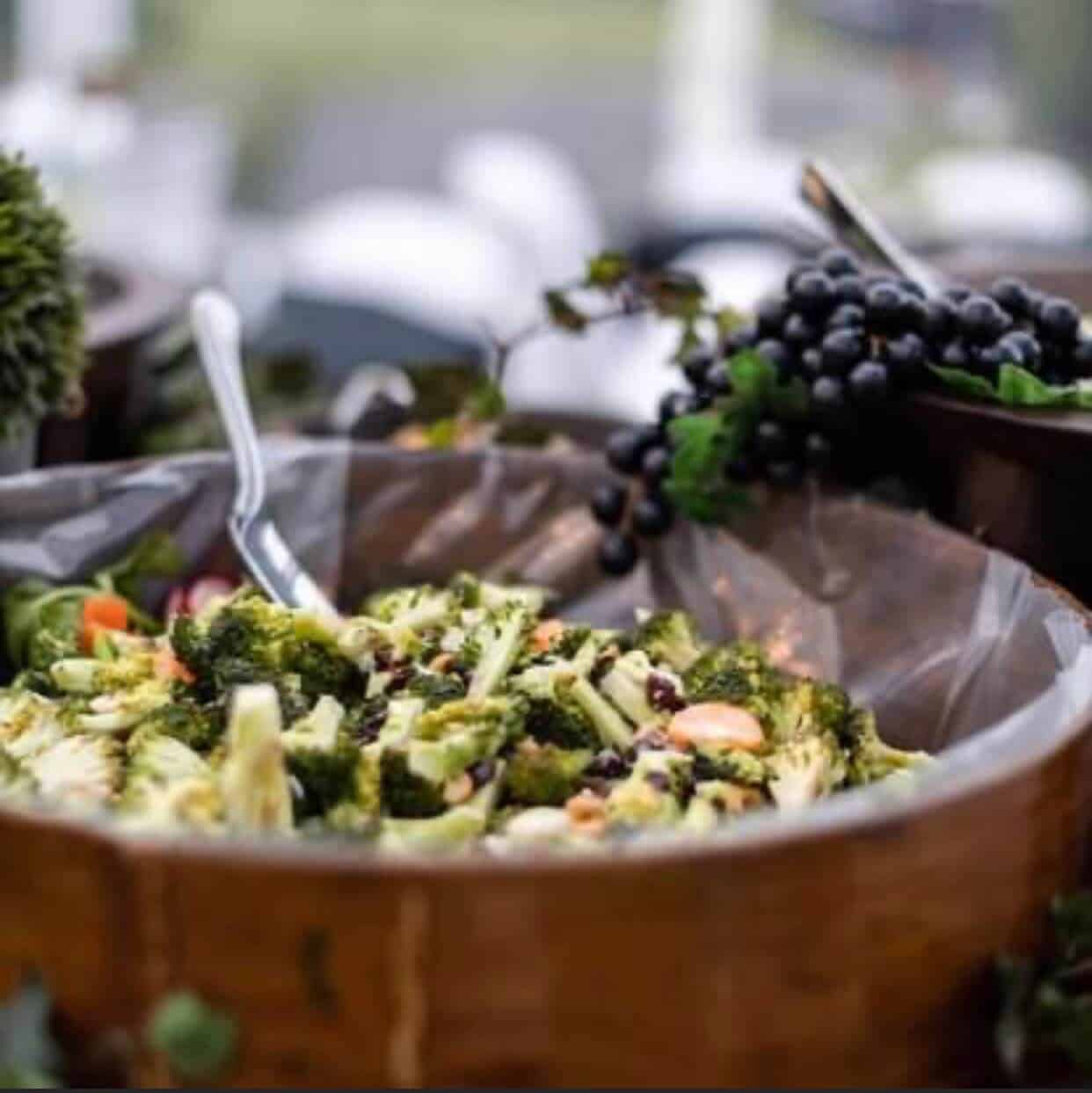 A bowl of broccoli and grapes on a table.