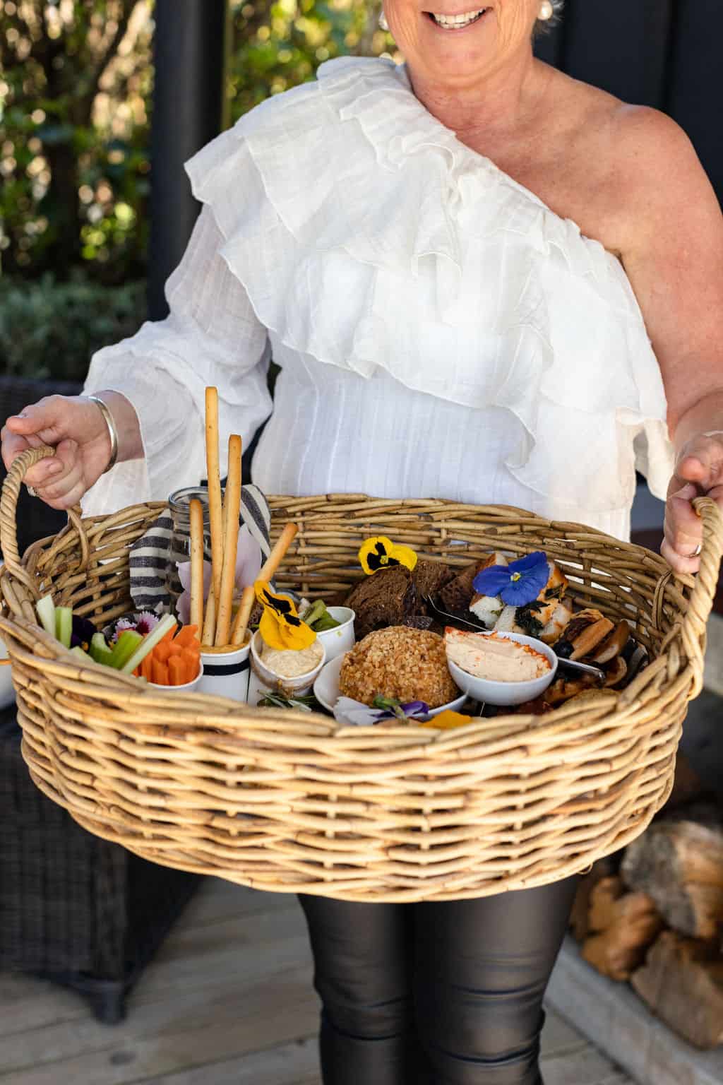 A woman holding a wicker basket full of food.